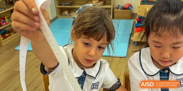 A young girl in a school uniform works on a drawing during a creative arts and crafts session at Benenden Bilingual School Guangzhou