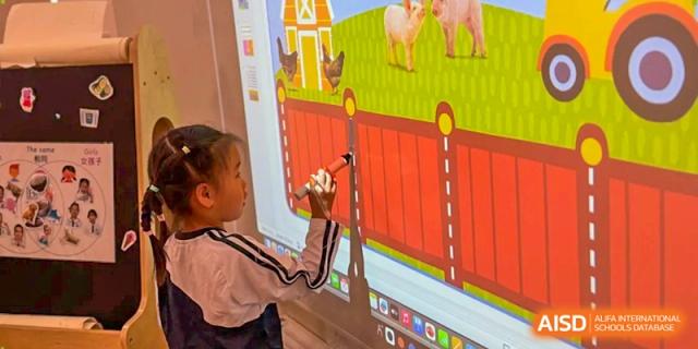 A young student uses a digital pen to interact with a colorful farm-themed display on an interactive whiteboard at Benenden Bilingual School Guangzhou