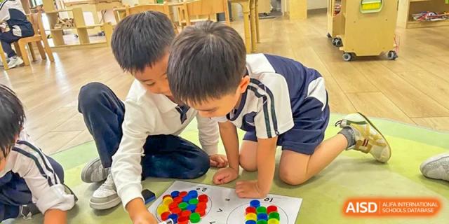 Two students work together at a table to sort and arrange colorful bottle caps as part of a counting exercise at Benenden Bilingual School Guangzhou