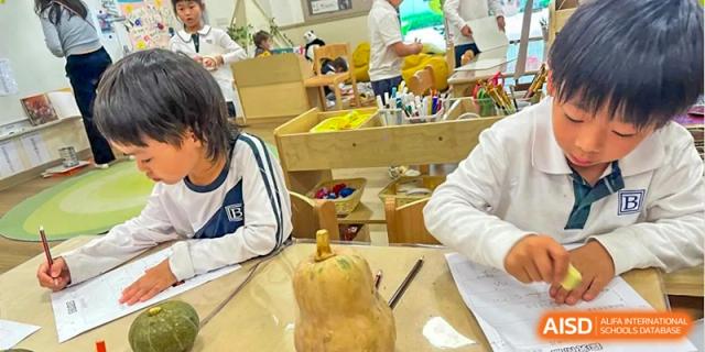 A young student sits at a wooden table and focuses on a hands-on activity involving a large textured pumpkin at Benenden Bilingual School Guangzhou