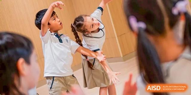 Students participate in an active physical movement or dance session in a bright and spacious indoor hall at Benenden Bilingual School Guangzhou