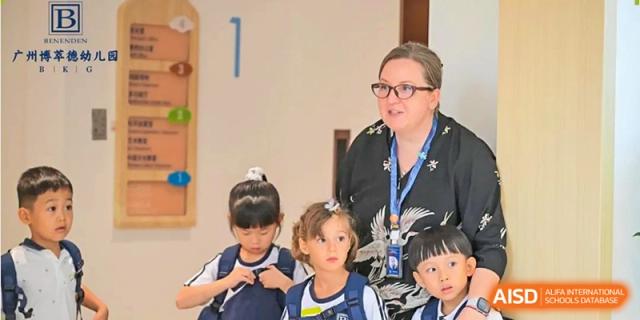 A teacher in a blue lanyard interacts with a small group of young girls during a morning meeting or lesson at Benenden Bilingual School Guangzhou