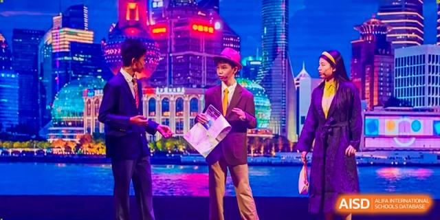 A young boy in a suit and purple hat performs on a stage in front of a digital city skyline backdrop at Benenden Bilingual School Guangzhou
