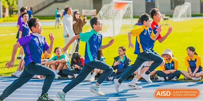 A student in a blue and teal athletic uniform sprints across an outdoor running track during a race at Benenden Bilingual School Guangzhou