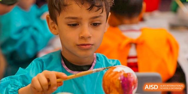 A young student concentrates on painting a colorful sphere during a creative arts and crafts lesson. Deutsche Botschaftsschule Peking