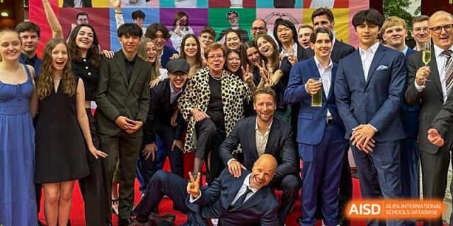 A large group of faculty and staff in formal attire pose for a fun and energetic group photo. Deutsche Botschaftsschule Peking