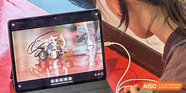 A tablet screen displays a robotic vehicle project being tested on a red surface during a technology lesson. Deutsche Botschaftsschule Peking