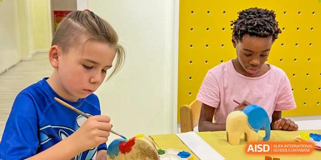 A young student concentrates on painting a ceramic figure with a brush during a creative art lesson. Deutsche Botschaftsschule Peking