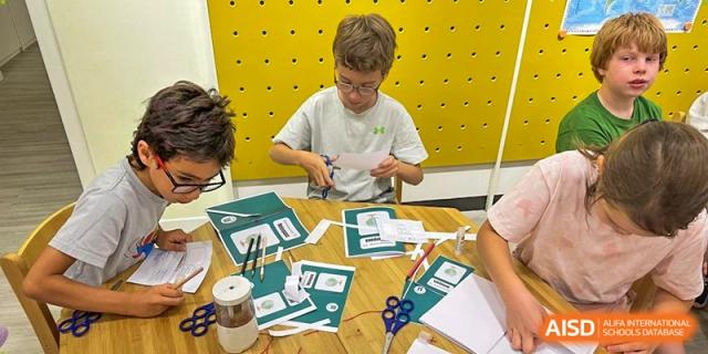 Students practice their fine motor skills by carefully cutting out paper shapes for a class assignment. Deutsche Botschaftsschule Peking
