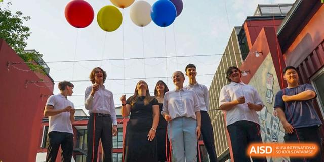 Students gather outdoors to release colorful balloons into the sky during a joyful graduation tradition. Deutsche Botschaftsschule Peking
