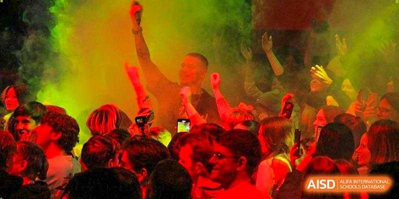 Students enjoy a vibrant event with red lighting and atmospheric smoke effects at the Deutsche Botschaftsschule Peking.