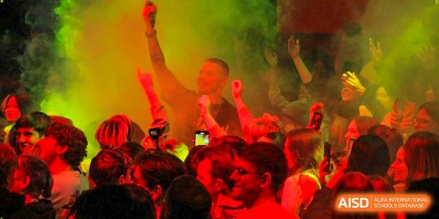 Students enjoy a vibrant event with red lighting and atmospheric smoke effects at the Deutsche Botschaftsschule Peking.