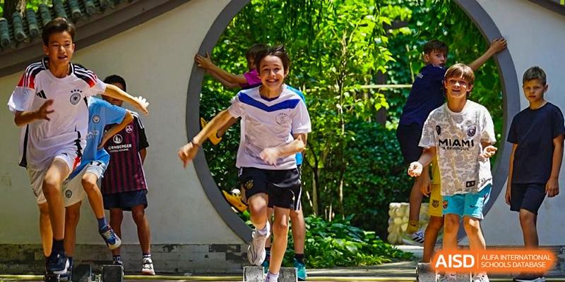 A young student runs joyfully through a circular garden gate during an outdoor activity at the Deutsche Botschaftsschule Peking.