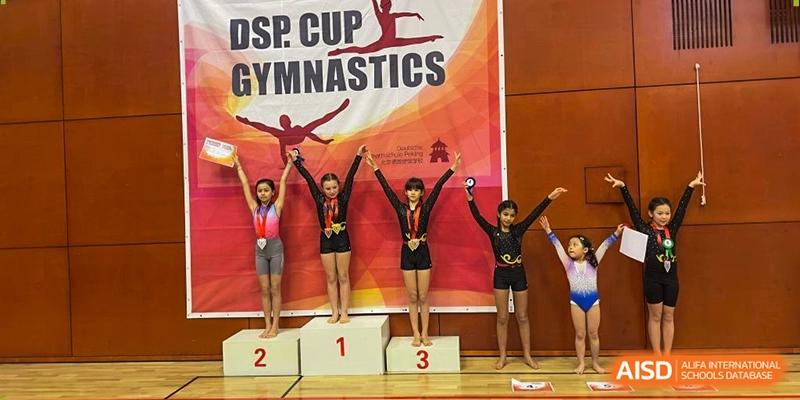 Young gymnasts stand on a winner's podium during the DSP Cup Gymnastics competition at the Deutsche Botschaftsschule Peking.