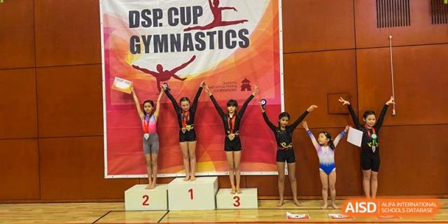 Young gymnasts stand on a winner's podium during the DSP Cup Gymnastics competition at the Deutsche Botschaftsschule Peking.