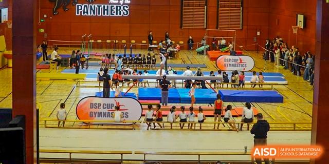 A wide view of the school gymnasium filled with students and equipment during the official DSP Cup Gymnastics event. Deutsche Botschaftsschule Peking