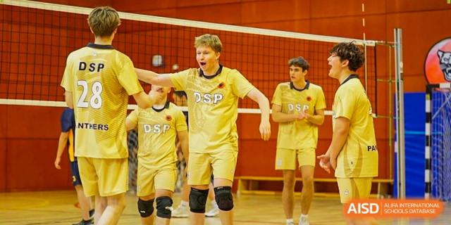 Students in yellow DSP jerseys celebrate a point with high-fives during a volleyball match. Deutsche Botschaftsschule Peking