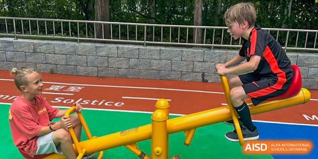 A student uses outdoor exercise equipment on the school grounds near the athletic track. Deutsche Botschaftsschule Peking