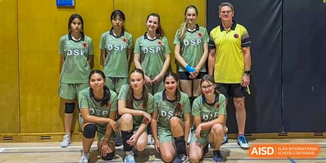 The girls' volleyball team poses for a group photo with their coach in the school gymnasium. Deutsche Botschaftsschule Peking