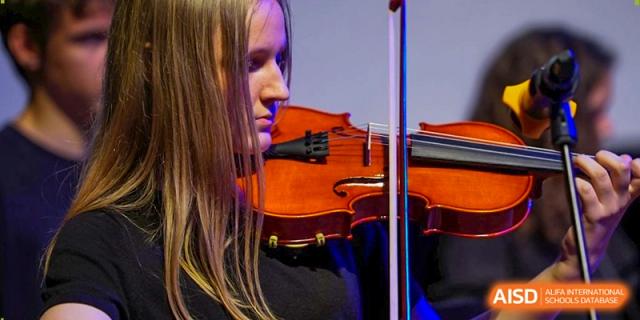 A close-up shot of a student violinist focusing intently on her performance during a school concert. Deutsche Botschaftsschule Peking