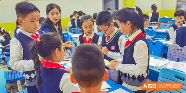 A group of students in matching navy and white uniforms collaborate on a hands-on project at their desks at Harbin Meijia Foreign Language School.