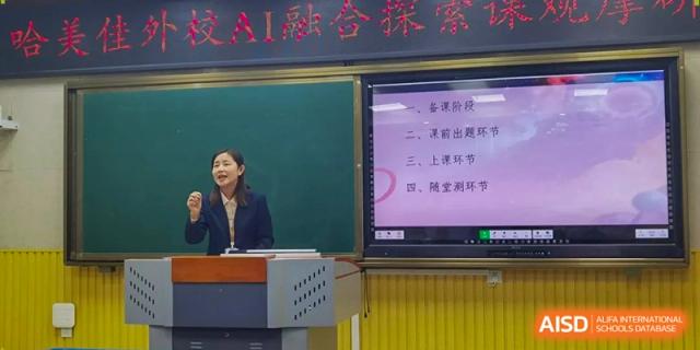 An instructor stands next to a podium and a large digital monitor while leading a seminar on technology in education at Harbin Meijia Foreign Language School.