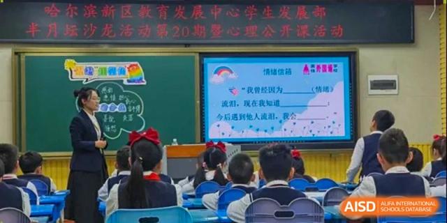 Children sit in class watching an interactive presentation on a large screen at the front of the room at Harbin Meijia Foreign Language School.