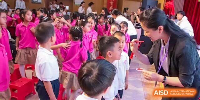 A group of young students in bright pink polo shirts gather together for a communal event in the school hall at Harbin Meijia Foreign Language School.