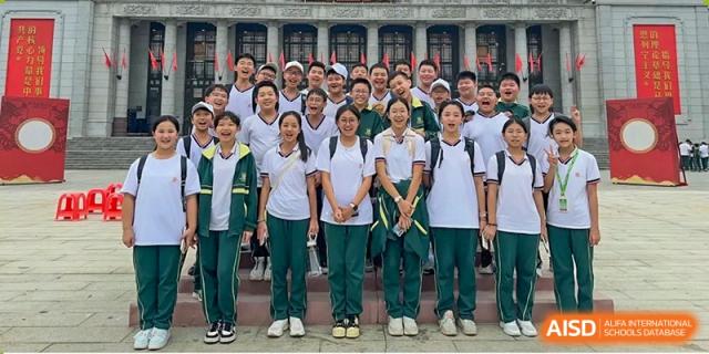 A group of students in white and green athletic uniforms smiling and posing together outdoors at Maple Leaf International Schools - Hainan