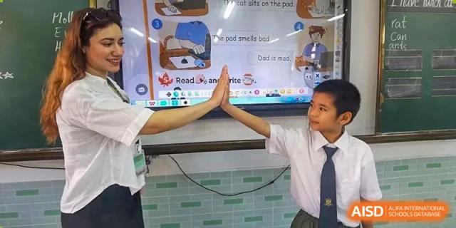 A student and teacher giving each other a high-five in front of an interactive whiteboard at Maple Leaf International Schools - Hainan