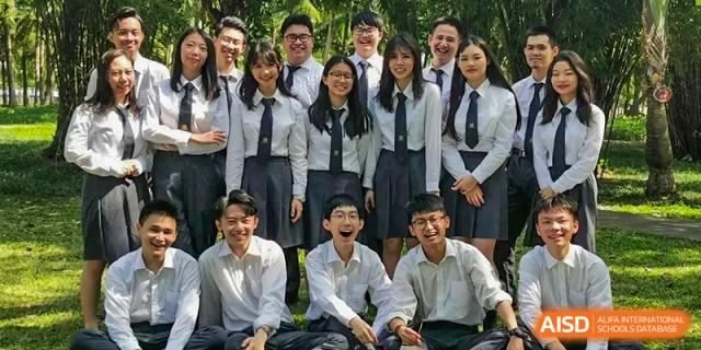 A group of students in white shirts and ties smiling and posing for a group photo outdoors at Maple Leaf International Schools - Hainan