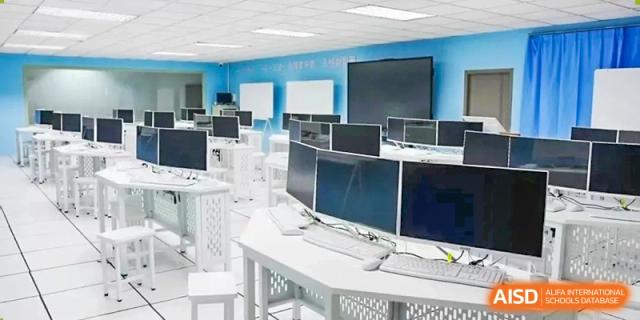 A clean and modern computer lab featuring white desks and several black monitors at Maple Leaf International Schools - Hainan