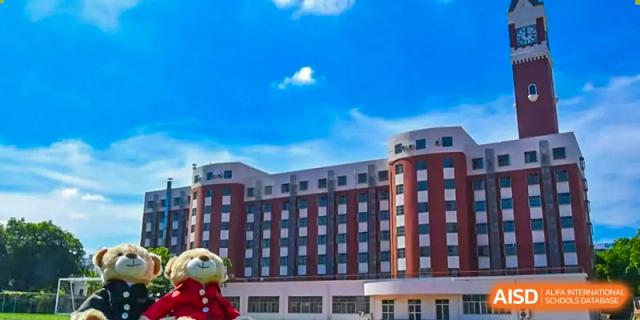 A multi-story school dormitory or classroom building with a red and white facade under a blue sky at Maple Leaf International Schools - Hainan