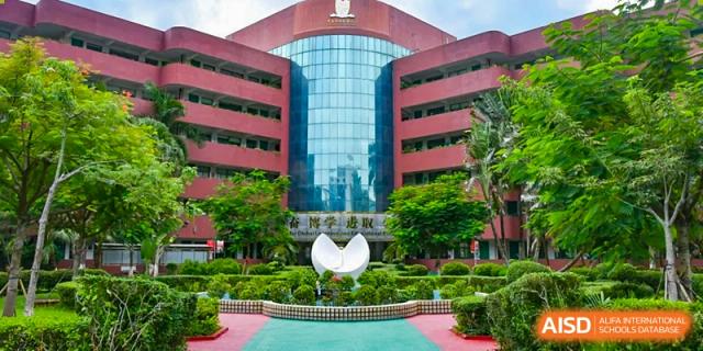 The main entrance of a large brick school building with a white sculpture in the foreground at Maple Leaf International Schools - Hainan
