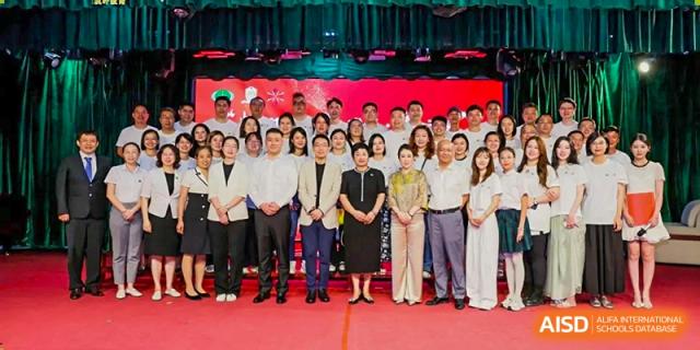 A large group of staff and officials in professional attire posing for a formal photo on a red carpet at Maple Leaf International Schools - Hainan