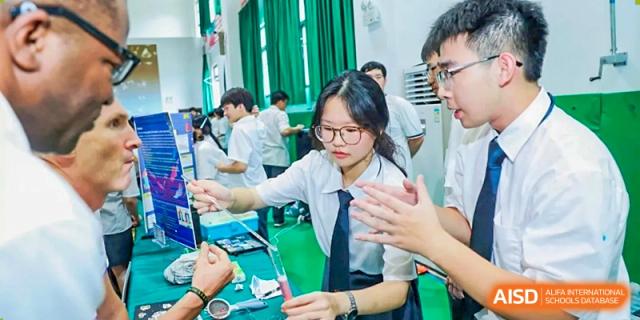A female student wearing glasses and a school uniform working on a science project in a classroom lab at Maple Leaf International Schools - Hainan