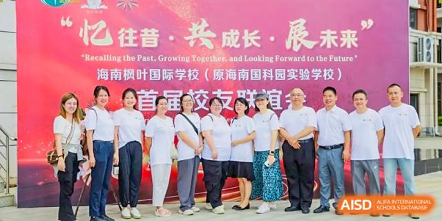 A group of adults in white t-shirts standing together in front of a pink banner with Chinese text at Maple Leaf International Schools - Hainan