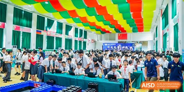 A large room filled with students working on laptops under a ceiling decorated with colorful banners at Maple Leaf International Schools - Hainan
