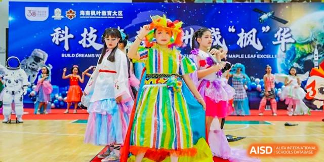 A young girl in a colorful striped dress and bright floral headpiece performing on stage at Maple Leaf International Schools - Hainan