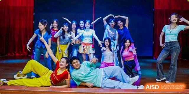 A group of expressive teenagers in colorful trendy outfits pose together on stage after a performance Maple Leaf International Schools - Hainan