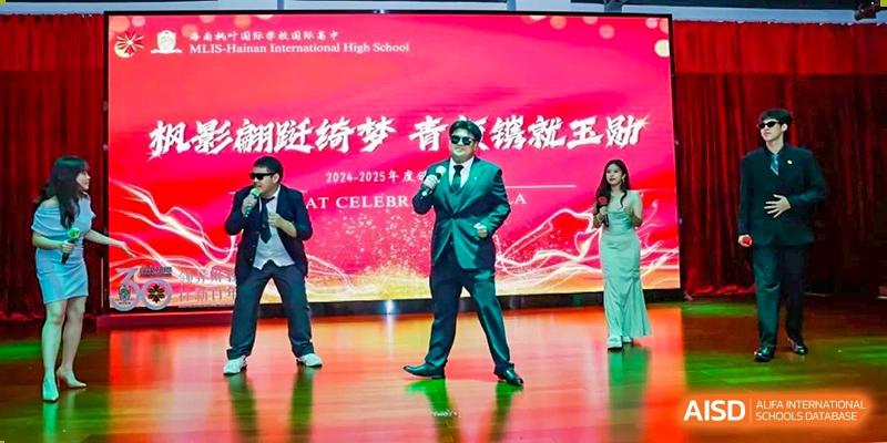 A male student in a sharp green suit and sunglasses performs on a brightly lit stage during a school gala Maple Leaf International Schools - Hainan