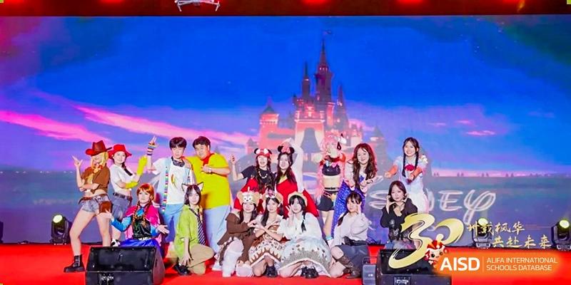 A large group of students in various costumes pose together in front of a castle backdrop during a school event Maple Leaf International Schools - Hainan