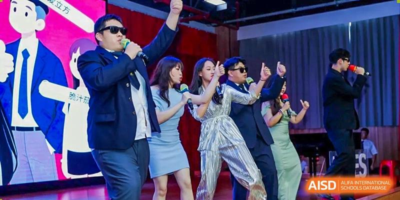 Students perform an energetic singing and dancing routine on stage in stylish outfits during a gala Maple Leaf International Schools - Hainan