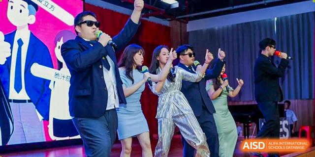 Students perform an energetic singing and dancing routine on stage in stylish outfits during a gala Maple Leaf International Schools - Hainan