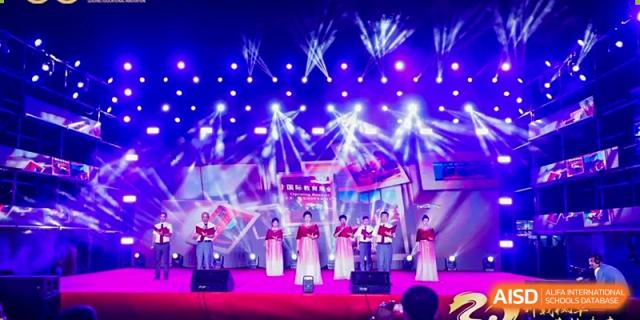 A choir of students performs on a stage illuminated by dramatic blue and white spotlights Maple Leaf International Schools - Hainan