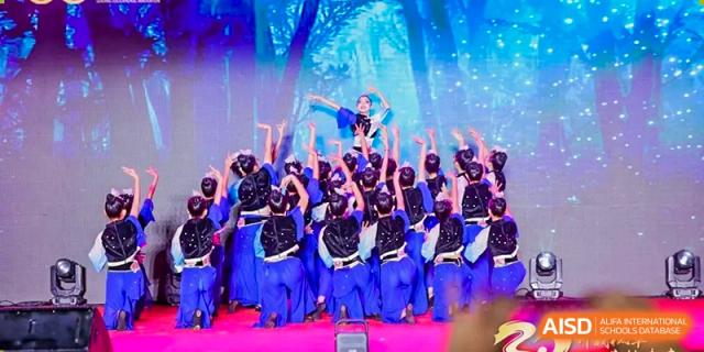 Dancers in blue and black outfits perform an expressive routine with a forest backdrop on stage Maple Leaf International Schools - Hainan