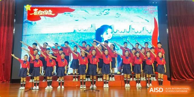 A school choir in red and black uniforms sings together in front of an animated blue background Maple Leaf International Schools - Hainan