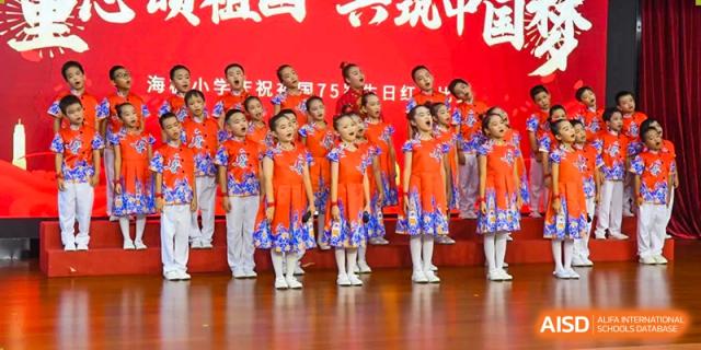 A close-up of a student choir in matching red floral dresses singing during a formal assembly at Maple Leaf International Schools - Hainan