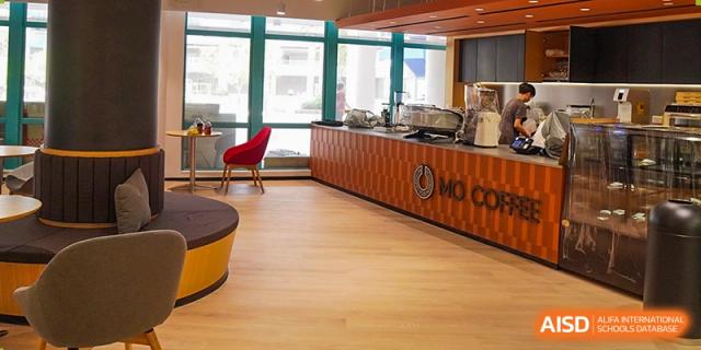 A modern, wood-paneled campus café and service counter with contemporary seating and large windows at Guangzhou ULink International School.
