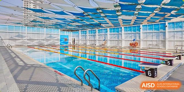A bright indoor swimming facility with a large lap pool and a distinctive blue and white geometric canopy roof at Guangzhou ULink International School.